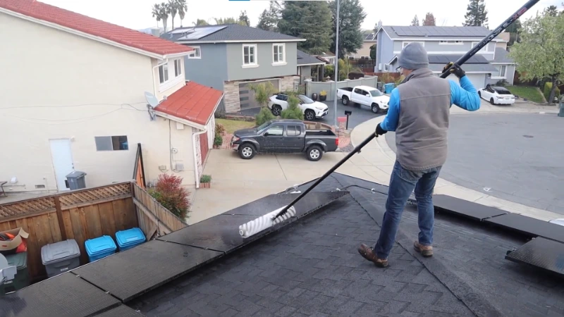 Technician cleaning solar panels on rooftop in San Clemente